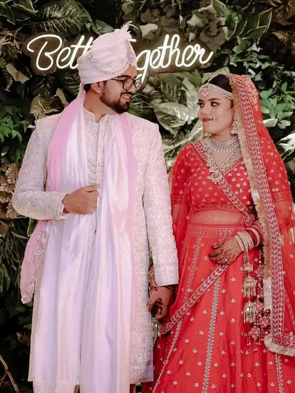 A beautiful portrait of Malvika and Prateek on their wedding day, standing in front of a "Better Together" neon sign.