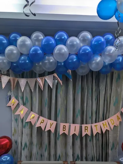 A close-up of the balloon garland and banner, showing the mix of transparent and solid blue balloons.