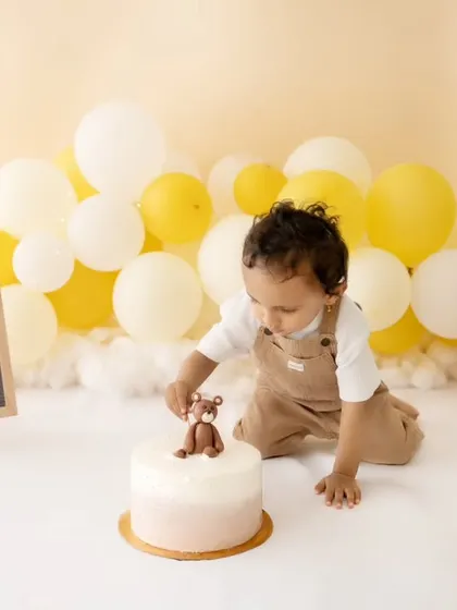 A sweet moment before the cake gets completely smashed. The simple setup with balloons and a teddy bear keeps the focus on the birthday boy.