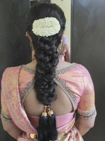 A thick, textured braid with a simple jasmine gajra and black tassels, creating a classic and elegant look.