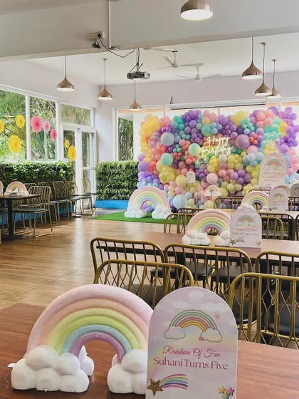 A wide view of the restaurant space transformed for Suhani's rainbow birthday. The massive balloon wall served as the focal point, with rainbow centerpieces on each table to continue the theme.