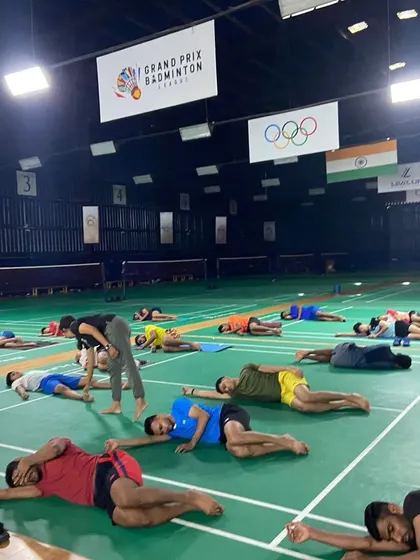 A yoga educator provides individual attention to an athlete during a stretching exercise. This personalized guidance ensures proper form and maximizes the benefits of each movement for better athletic performance.