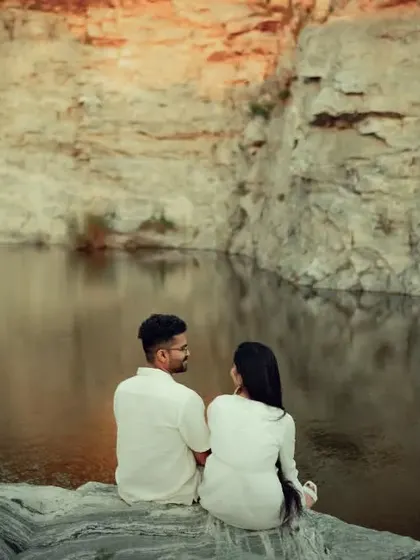 A peaceful pre-wedding scene with the couple looking out over a quarry lake, their matching white outfits contrasting beautifully with the natural landscape.