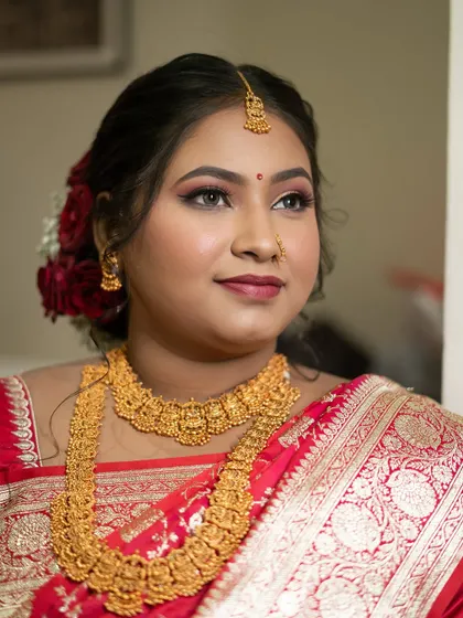 A close-up of a bride's classic look, featuring bold eyes and traditional gold temple jewelry.