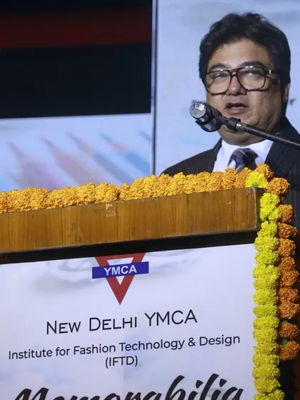 A senior faculty member addresses the gathering, sharing insights about the student collections.