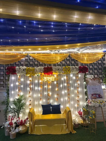 A Haldi setup on a terrace with a starry night effect. The decor uses blue and yellow drapes on the ceiling, with a lit-up backdrop for the main seating.