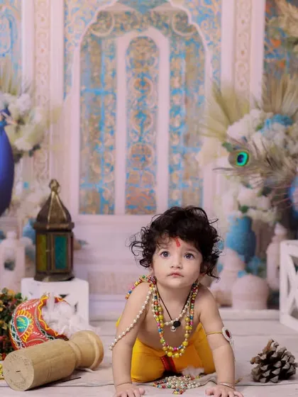 This little one looks up with wide, curious eyes, dressed as Krishna and surrounded by festive decor. A perfect shot capturing the wonder of childhood.
