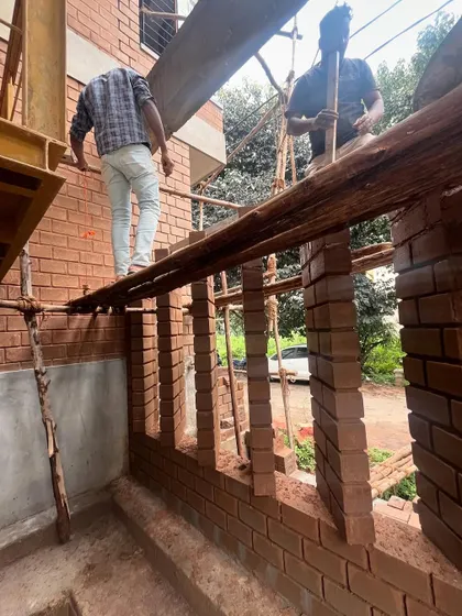 Masons carefully constructing a brick jaali wall. This kind of detailed work requires immense skill and is a hallmark of the craftsmanship we value in our projects.