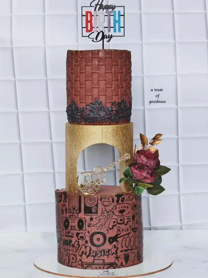 This music-themed cake combines several textures, including a basket-weave pattern and a hand-stenciled pop art design. The gold tier with a guitar cutout adds a touch of glamour to this creative birthday cake.