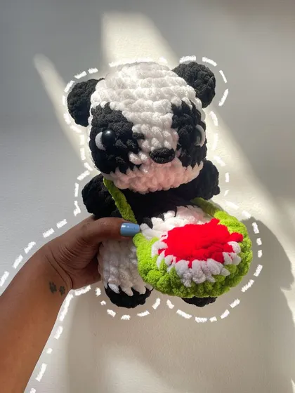 A cute panda plushie saying hi. This little guy is complete with a watermelon-slice bag, a fun and quirky custom detail requested by the client.