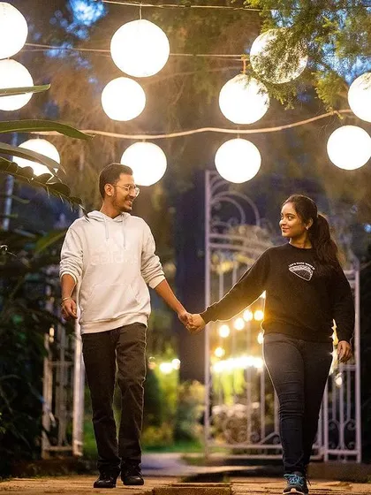 A romantic night shot of a couple walking hand-in-hand under a canopy of glowing lanterns.