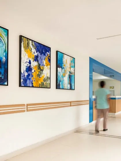 Art is integrated into this hospital corridor to provide a positive distraction and reduce the clinical feel. The vibrant paintings and clean lines create a space that is both functional for circulation and uplifting for users.