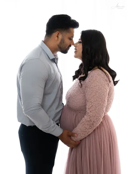 An intimate close-up. This high-key photo against a white background focuses entirely on the couple's connection as they prepare to become parents.