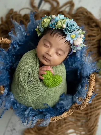 A lovely combination of green and blue. The baby is wrapped in a green swaddle, placed in a basket with blue textured fabric and cute pumpkin props.