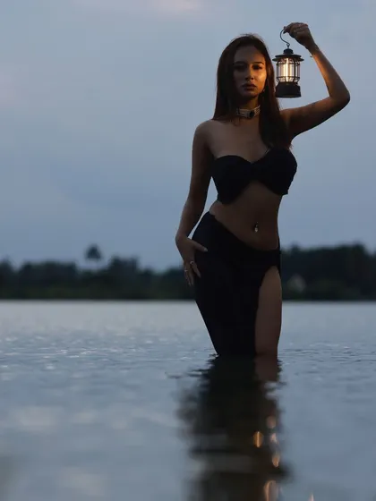 A wide shot taken as night falls, creating a dramatic silhouette of the model in the lake.