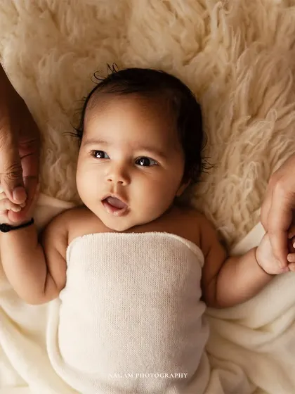 A newborn baby holds onto their parents' fingers. This close-up shot is a beautiful way to remember just how tiny their hands were.