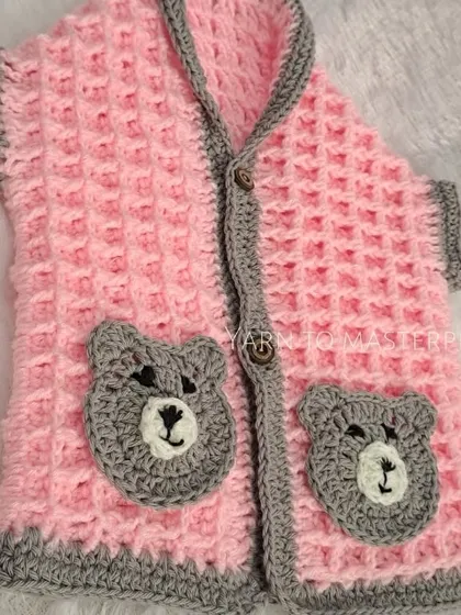 A front view of the pink and grey bear sweater vest, highlighting the textured waffle stitch and the cute, hand-stitched bear pockets that add so much personality.