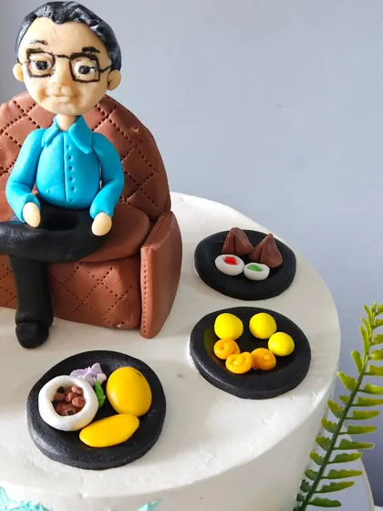 Another angle of the personalized toppers, showing the arrangement of the dad figurine and his miniature plates of food. Each element is carefully placed to create a complete, story-driven scene.