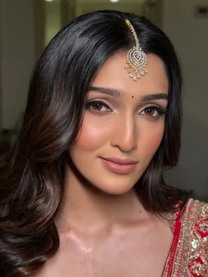 A close-up of a modern red bridal look. The focus here is on flawless skin and sharp, clean lines with a winged eyeliner and softly contoured features, proving that a traditional red lehenga can be both classic and contemporary.