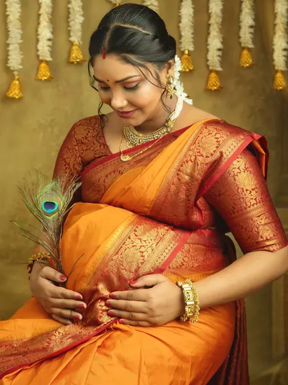 A tender moment, looking down at your bump. This portrait captures the deep, personal connection between a mother and her unborn child, framed by the beauty of a traditional saree.