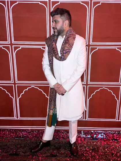 An elegant Diwali look featuring a white bandhgala paired with a luxurious pashmina shawl, demonstrating how to layer accessories for a sophisticated festive outfit.