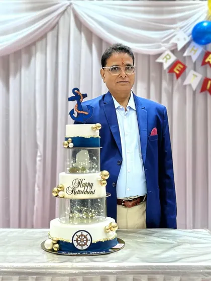 A proud moment for the retiree, standing next to the cake that celebrates his years of service.