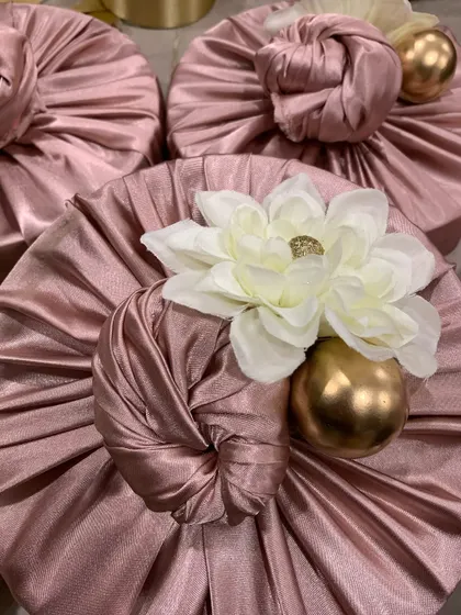 Luxurious pink satin Furoshiki wrapping, topped with a white flower and a golden accent ball. This style of gift wrapping adds a touch of class to any present.