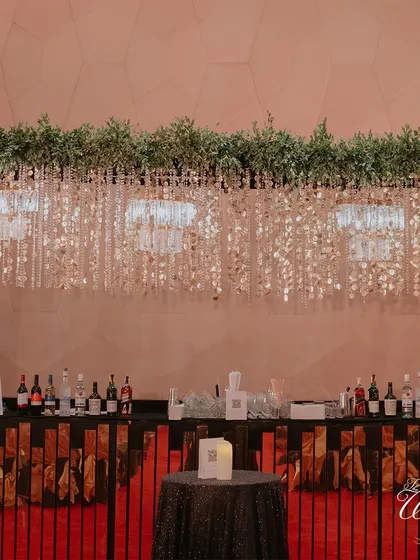 The bar setup is a key part of the decor. Here, a stunning overhead installation of crystals and greenery elevates the space, making it a focal point of the evening.