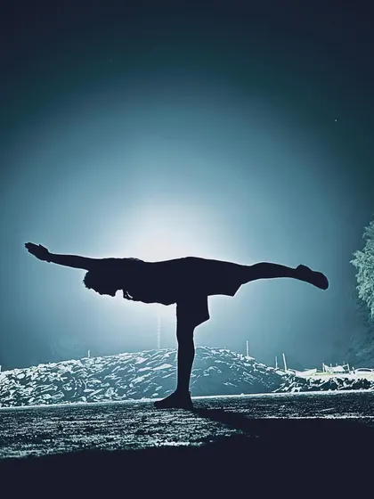 Practice comes first. A silhouette of Virabhadrasana III (Warrior III) against the night sky.