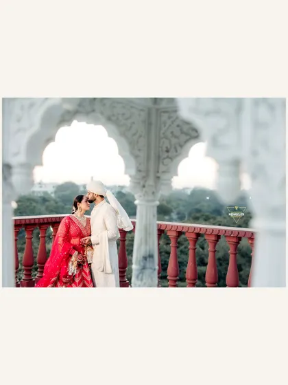 A wide shot capturing the couple sharing a kiss on an ornate balcony. Using the arches as a natural frame, this photo emphasizes both the romance of the moment and the beauty of the destination wedding location.