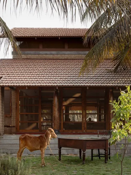 The roof design uses double Mangalore tiles for insulation, a sustainable practice that helps regulate the indoor climate. The verandahs are supported by graceful wooden columns restored from heritage homes in Karaikudi, blending history with contemporary design.