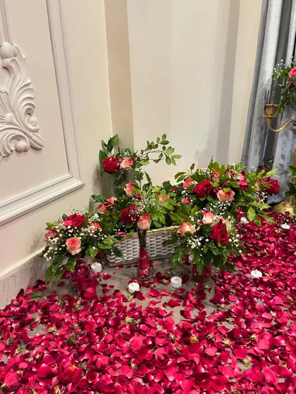 Another detail from the romantic room setup, showing flower baskets placed on the floor amidst a sea of red rose petals and candles.