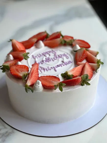 A simple and elegant strawberry cream cake. The clean white frosting provides the perfect canvas for the fresh, bright red strawberries on top.