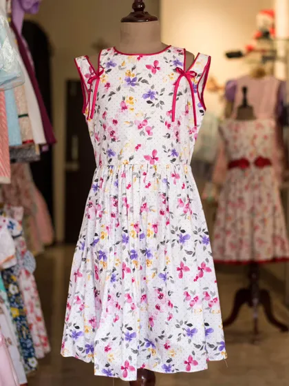 Another view of the white floral cold-shoulder dress, highlighting the playful ribbon details and the beautiful, colorful print.