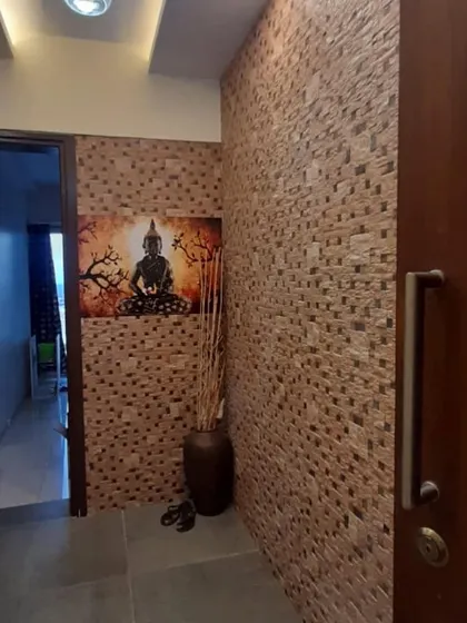 The entrance to a home sets the tone. This entryway features a textured stone wall and a serene Buddha painting, creating a peaceful and welcoming first impression.
