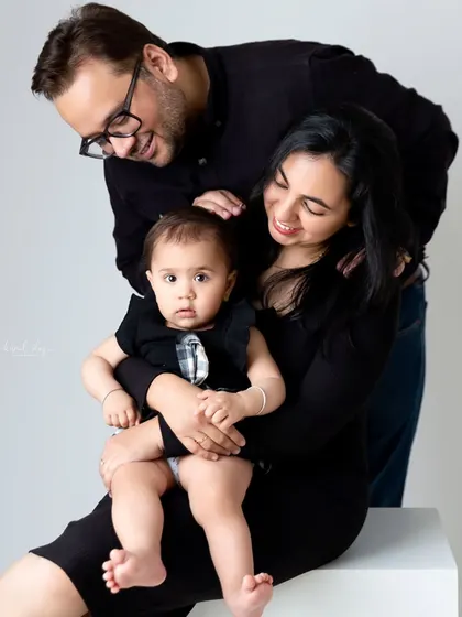 A black and white version of a family portrait, emphasizing the loving expressions of the parents looking at their child.