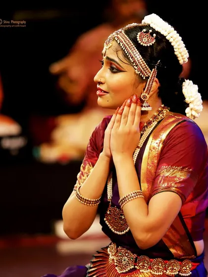 A close-up of a moment of prayer and gratitude on stage, with the orchestra visible in the background.