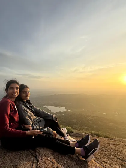 Two friends sitting together, enjoying the spectacular sunrise from the peak of Uttari Betta.