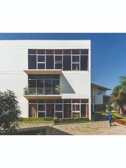 The main office block, featuring a multi-level facade with deep-set windows and balconies. This design responds to the climate by providing shade and creates a formal yet inviting presence as part of the campus master plan.