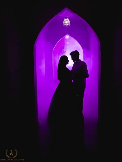 A dramatic silhouette of a couple framed by an archway filled with vibrant purple smoke. This shot demonstrates our creative approach, using props and lighting to create moody, artistic pre-wedding portraits.
