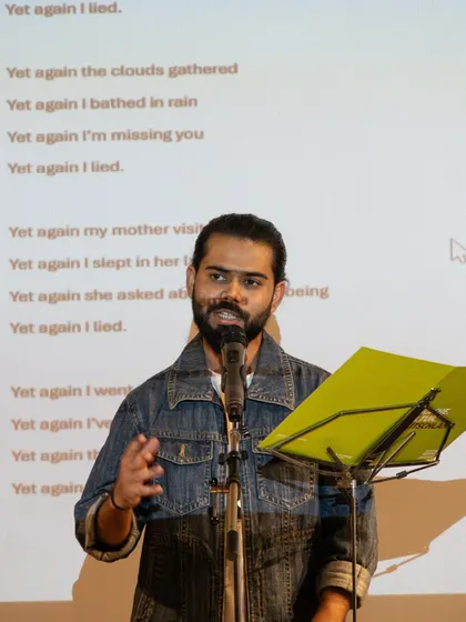 A poet performing his piece 'Yet again I lied' with his poem projected behind him. We encourage creative and multimedia approaches to spoken word performance.