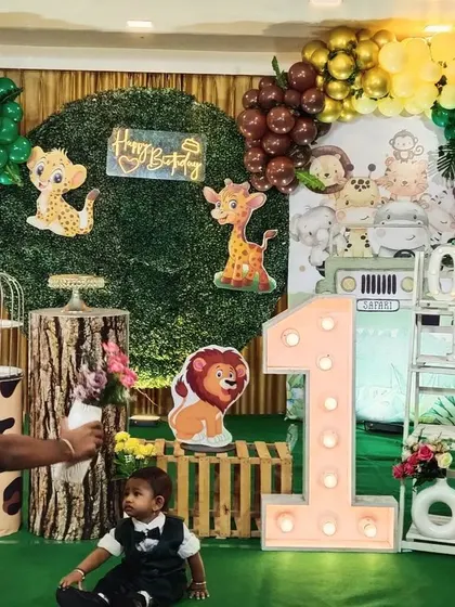 The birthday boy exploring his jungle-themed party. The large light-up '1' and animal props create a fun play area.