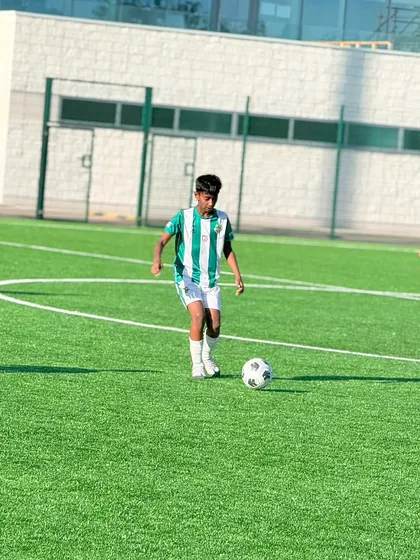 A young Kickstart player confidently on the ball during an international friendly match in London, a valuable experience for his development.