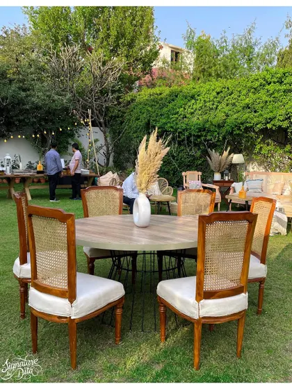 Guest seating was arranged to encourage conversation, with round tables and classic cane-back chairs creating an elegant dining setup on the lawn.