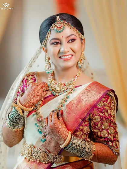 A portrait of the bride looking radiant and happy in her beautiful white and pink wedding saree.