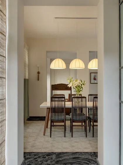 A view into the bright and airy dining room. The space is framed by a doorway, creating a sense of procession and highlighting the clean, minimalist interior design.