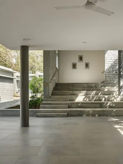 The open, columned corridors and wide steps create multi-functional spaces for informal gathering and movement, filled with dappled light.