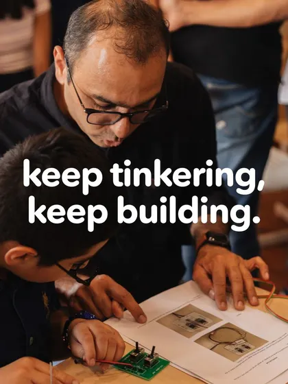 Keep tinkering, keep building. A father and son work together on a robotics project, learning about circuits and engineering. We encourage this kind of collaborative problem-solving.