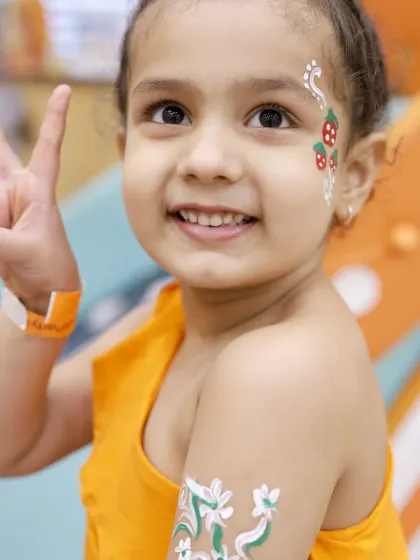 A happy guest shows off her new face and arm paint. Our temporary tattoos and face painting are done with skin-safe, non-toxic materials.