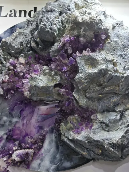 A sculpture by Maria Molaei featuring a large rock formation with purple amethyst crystals.